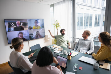 Group of business professionals sitting in meeting room and discussing during virtual meet