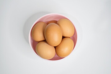 Top view of chicken eggs in the pink bowl isolated on white background