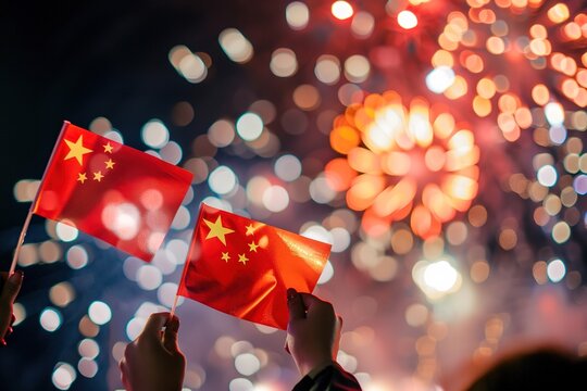 Hands holding Chinese flags against fireworks