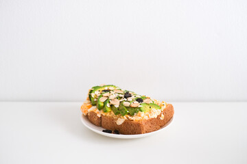 Avocado sandwich with scrambled eggs, sliced avocado and egg on toasted bread for healthy breakfast or snack.