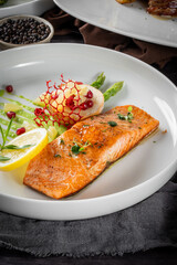 Delicious grilled salmon with a side of mashed potatoes, garnished with lemon and herbs on a white plate.
