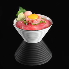 Delicious Japanese sashimi bowl topped with fresh seafood and a raw egg, styled with green garnish, presented on a black background.