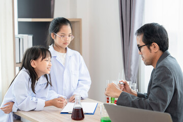 adorable asian elementary school girls in science gown learning chemical laboratory with teacher in class