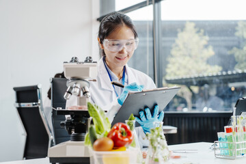 Two female researchers in the lab work at a desk on plant genetic modification for food, meat, and vegetables, utilizing advanced genetic engineering technology to enhance crops and animal feed.