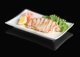 Delicious plate of sliced grilled chicken served with lemon, pickled ginger, and fresh lettuce on a...