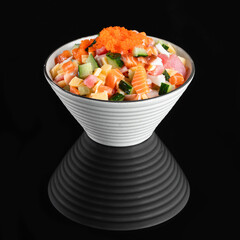 Delicious poke bowl with fresh vegetables, diced seafood, and fish roe, served in a white ceramic...