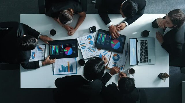 Time lapse of business people analyze financial chart at meeting. Top down aerial view of smart people looking at statistic graph with stock market data document scatter at meeting table. Directorate.