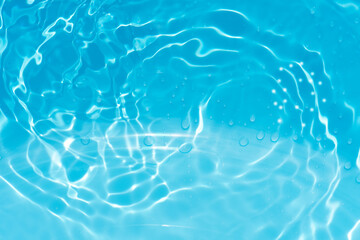 Blue water with ripples on the surface. Defocus blurred transparent blue colored clear calm water surface texture with splashes and bubbles. Water waves with shining pattern texture background.