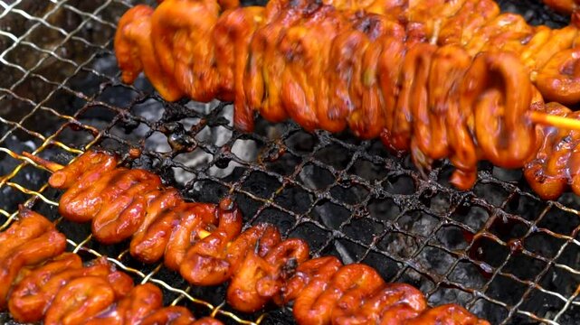 slow motion of flipping chicken intestine on the grill; a famous Filipino street food 