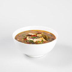 Delicious spicy soup in a white bowl, garnished with fresh vegetables and herbs. Perfect for a comforting meal.