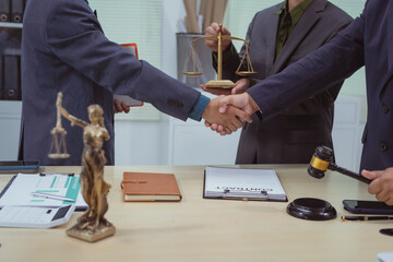 Three lawyers in a meeting at the table in an office, shaking hands discussing business, focusing...