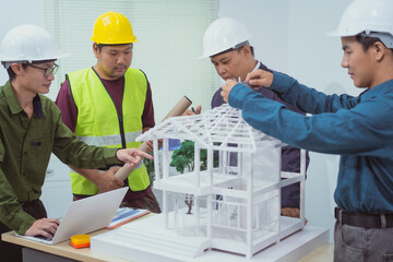 A male engineer and  contractor at a desk in an office discuss the structural design of a...