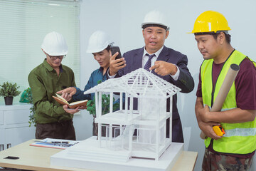 A male engineer and  contractor at a desk in an office discuss the structural design of a...