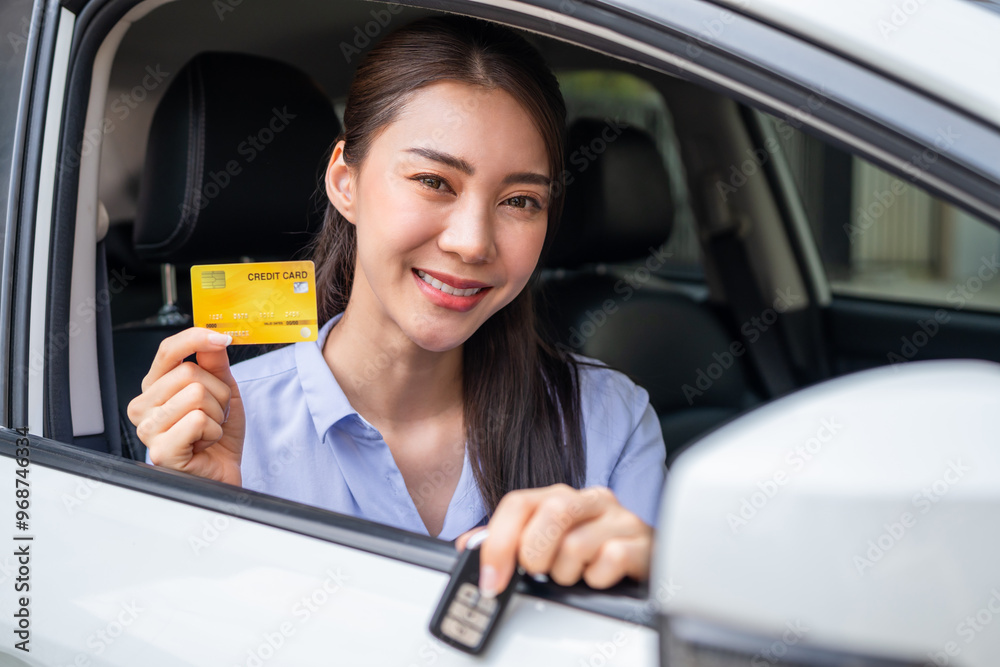 Wall mural portrait of asian woman driver holding credit card while sitting in car.