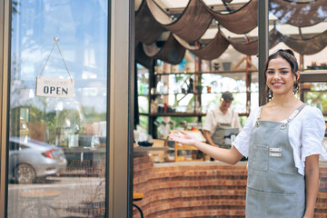 Portrait of Latino woman waiter standing and looking at camera in cafe.