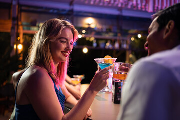 Beautiful young couple having fun, drinking alcohol cocktail in a bar. 