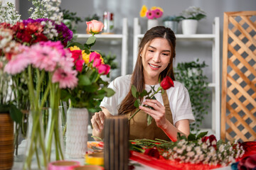 Fototapeta premium Asian young florist girl completing beautiful bouquet in flower shop. 