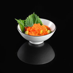 Elegant gourmet dish featuring finely chopped vegetables garnished with fresh green herbs served in a stylish white bowl on a black background.