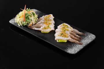 Elegant plating of gourmet sashimi with shredded vegetables and garnish on a black background, perfect for culinary and food presentation themes.