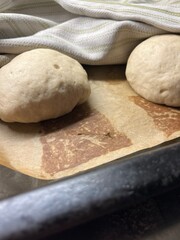 Two bread buns on baking paper and sheet before going into oven.