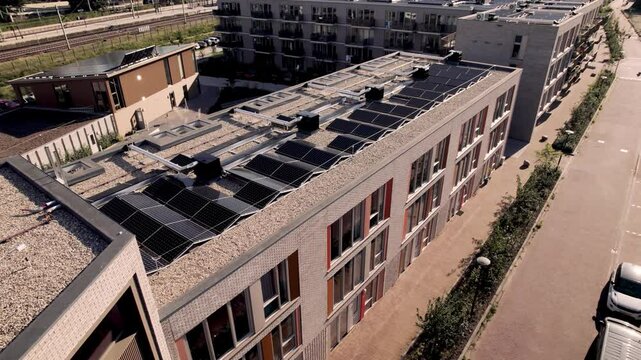 Slow following of street with entrance of housing complex and rooftops full of solar panels seen from above. Dutch engineering and real estate market. Street view.