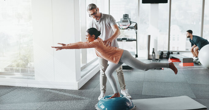 Physiotherapy, woman and personal trainer in gym for balance, rehabilitation and stability training. Man, client and half ball in fitness center for core strength, yoga practice and help in exercise
