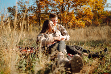 A couple enjoys a joyful moment together on a serene autumn day in a colorful forest setting with vibrant foliage and soft sunlight. The concept of youth, love and lifestyle.