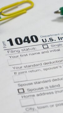 Form 1040 used for reporting individual income taxes. Paperclip and pen near upper corner. Common tool for annual tax filing in the United States