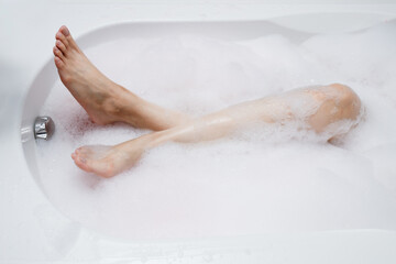 Woman legs in bath bomb foam. Top view closeup body part. Enjoying and relaxation in spa hotel resort.