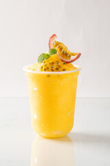Refreshing chilled passion fruit drink in a plastic cup, garnished with fresh mint and passion...