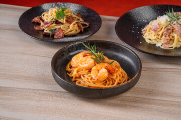 Three delicious plates of Italian pasta dishes with different toppings, set on a wooden table, perfect for a culinary-themed stock photo.