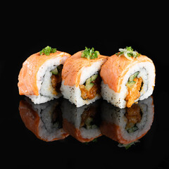 Three pieces of delicious sushi rolls with salmon and avocado on a reflective black surface, garnished with green herbs.