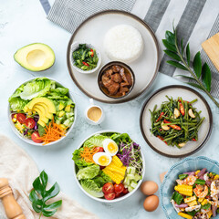 Top view of assorted healthy dishes, fresh salads, and vegetables on a light background, perfect for a balanced diet and nutrition concept.