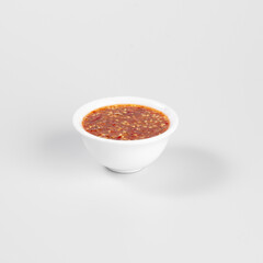 White bowl filled with spicy chili sauce on a plain white background, perfect for culinary and food-related projects.