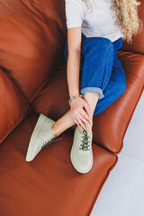 Female feet on sofa in beige leather slippers. Shoes for women.