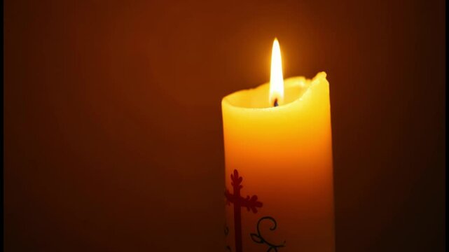 Glowing Paschal candle with rich designs, bokeh and warm golden light