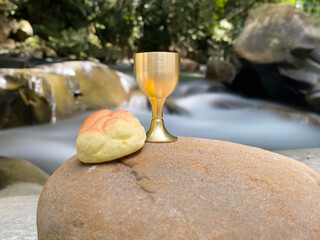 Holy Week, Lent Season, Maundy or Holy Thursday Concept - chalice and bread with nature background. Stock photo.
