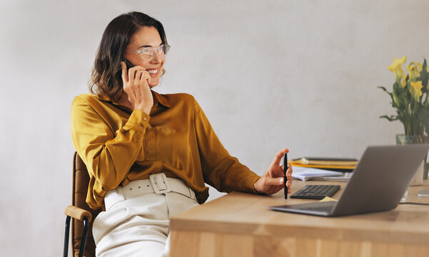 Professional communication: Happy businesswoman making a phone call in office