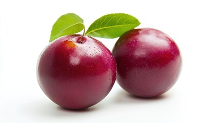 Fototapeta premium Two shiny red plums with green leaves on a white background.