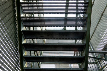 Fototapeta premium Steel staircase leading upward in an industrial building with natural light filtering through