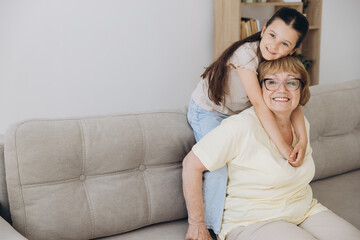 Cheerful cute granddaughter kid and happy grandma hugging with love, tenderness, affection, Grandmother embracing grandchild, enjoying family relationship.