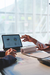 Team of business people pointing at digital tablets and pointing at charts on screen while explaining online marketing information to colleagues. Discussion. Consultation. Collaboration.