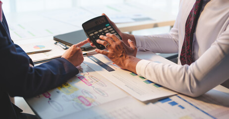 Two businessmen working together Analyze financial reports with charts and graphs while using the calculator to calculate budget, income, taxes, business growth. Startup business idea.