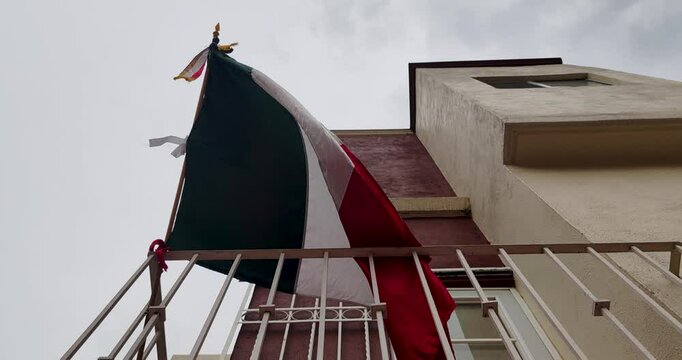 Mexican flag waving on a balcony of a house as part of the decoration of the national festivities in the month of September in Mexico