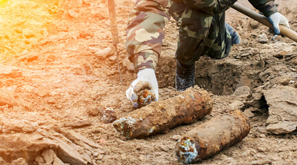 Military personnel extracting live mortar shell during demining operation