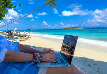 Nomad digital with laptop and running remotely with bright scenic view near poolside on the beach in summer time