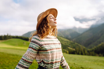 Young traveler woman enjoying the fresh mountain air in a scenic landscape while wearing a hat during the daytime. Travel, nature concept