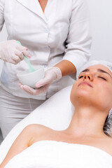 Naklejka premium Young woman wearing an alginate mask in a modern cosmetic center. Perfect for promoting innovative skincare treatments and deep hydration solutions.