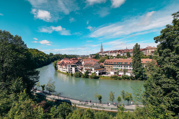 Fototapeta premium A panoramic view of the Aare River winding through Bern, Switzerland on a bright sunny day with vibrant greenery and historical architecture