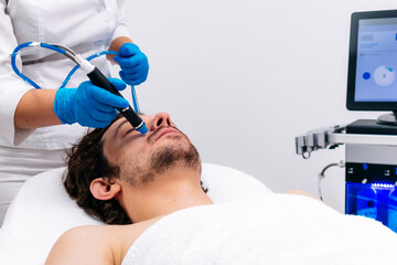 Man receiving a hydrafacial treatment in a modern cosmetic center. Innovative skin hydration and cleansing for visible rejuvenation. Perfect for promoting advanced skincare solutions.